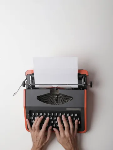 old fashioned typewriter with hands and blank paper