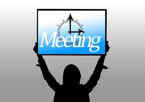 person holding a sign announcing a meeting 