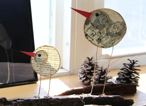 Two wire and paper birds on a log