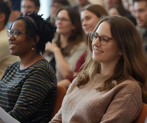 photo of people seated in an audience listening to a presentation