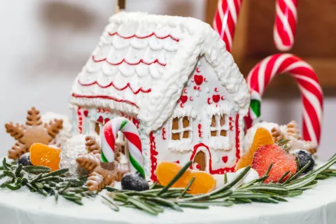 Photo of gingerbread house with icing and candy canes by Julia Filirovska